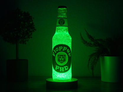 The PHD Flopper Perk a Cola Bottle Light by Bottle Light Company glows green between two plants, adding collectible Call of Duty Zombies charm to any dark room.